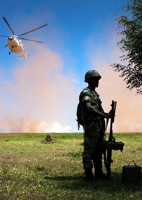 Soldier stands waiting while UN helicopter is landing 