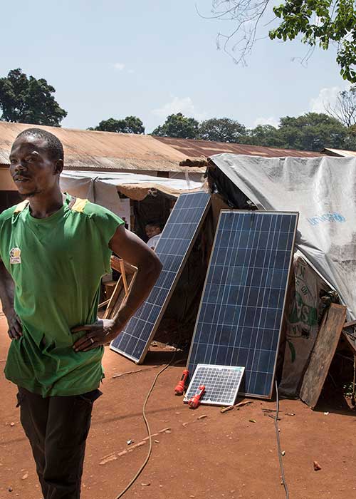 Man standing outside tent with solar panels in IDP camp Site du Petit Seminaire St.Pierre Claver in Bangassou, Central African Republic.