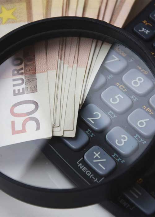 Magnifying glass over euro bills and a calculator