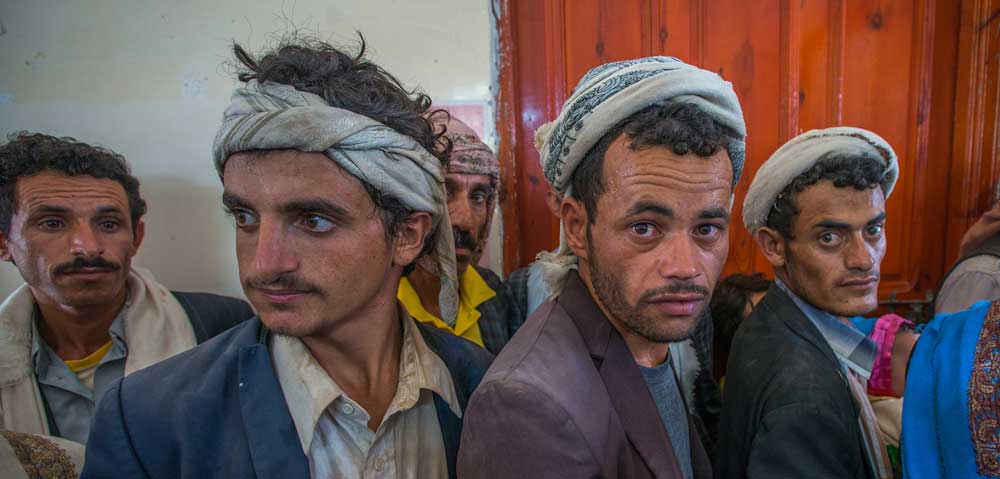 Yemeni fathers line up at a remote EU-supported clinic where they have brought their children.